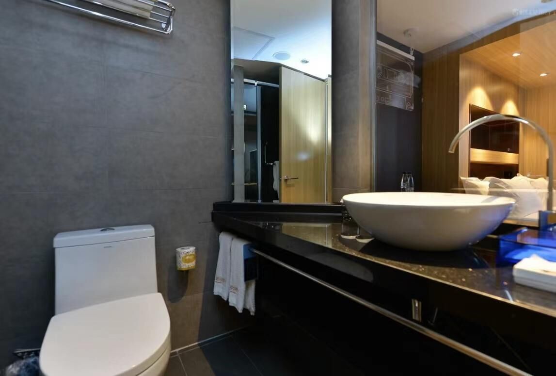 A modern bathroom with a toilet, a large sink, and a mirror.
