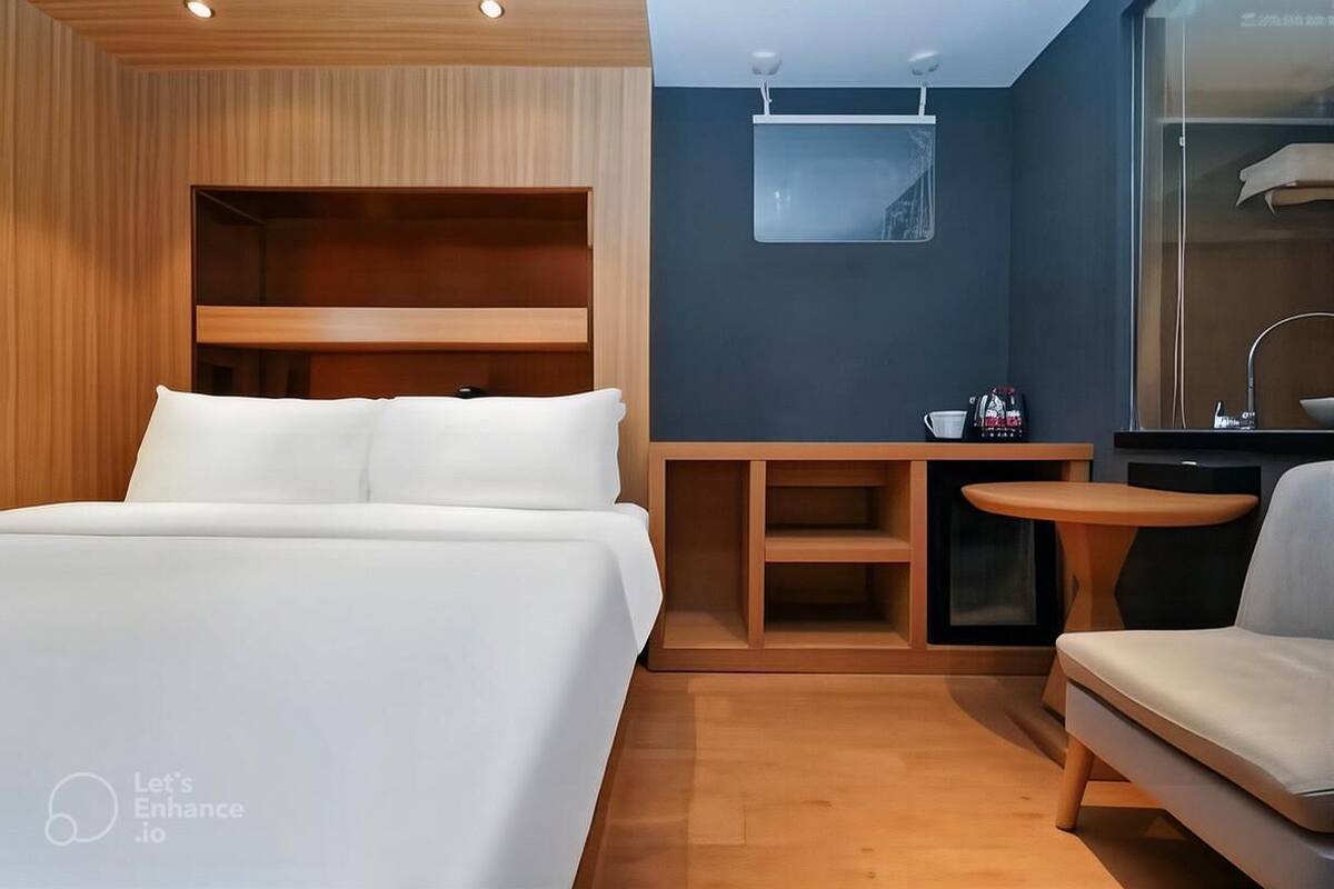 Een moderne hotelkamer met een groot bed, een klein bureau met stoel, een spiegel en een bijzettafeltje.