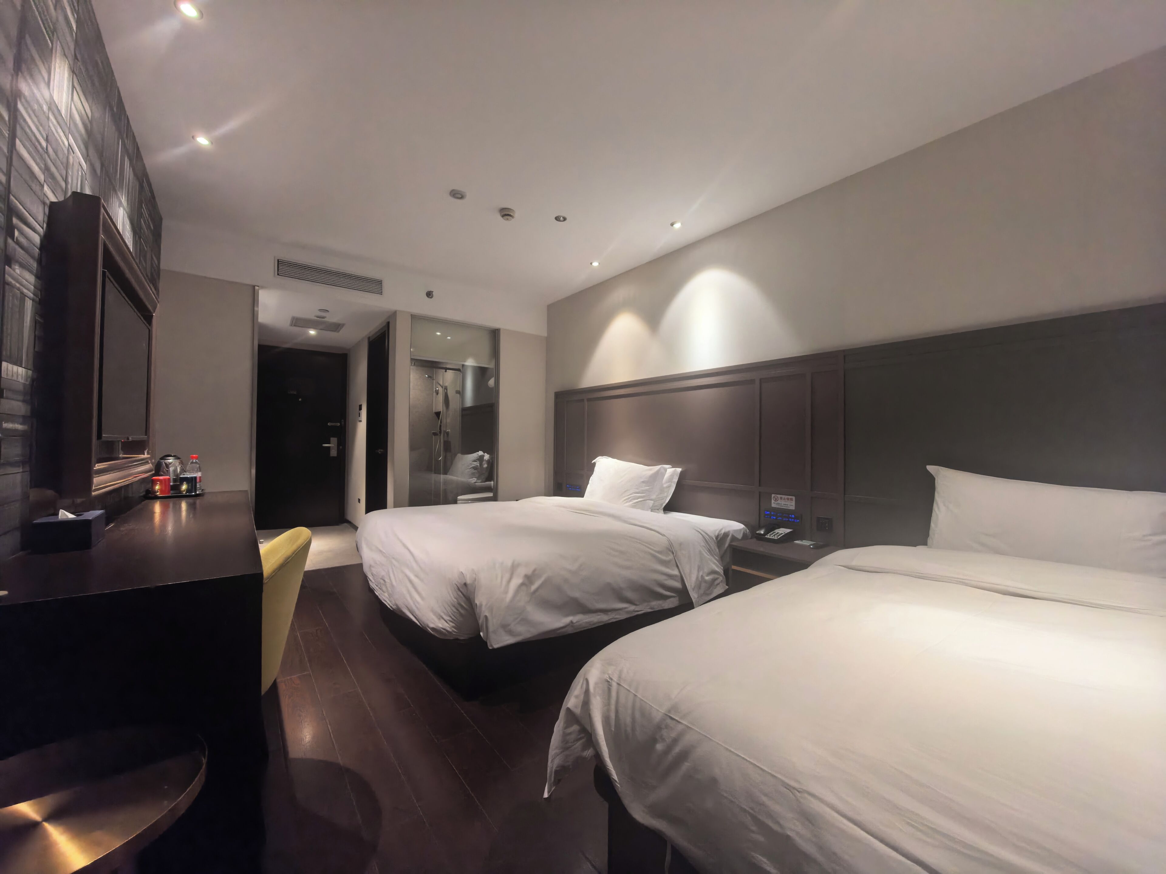 Une chambre d’hôtel moderne équipée de deux lits, d’un bureau et d’un espace douche.