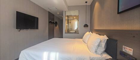 Habitación de hotel con una cama grande, televisión montada, teléfono junto a la cama y un espejo.