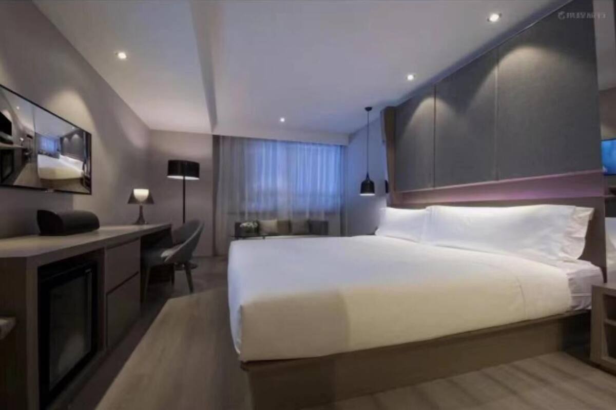Een moderne hotelkamer met een groot bed, een bureau met een computer, een stoel en een televisie.