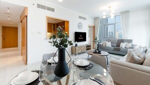 Una sala de estar moderna con comedor, un conjunto de sofás y un televisor montado en la pared.