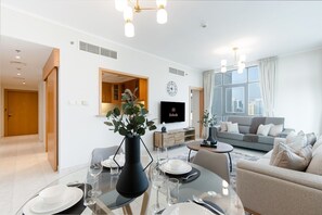 Ein modernes Wohnzimmer mit Essbereich, einer Sofagarnitur und einem an der Wand montierten Fernseher.