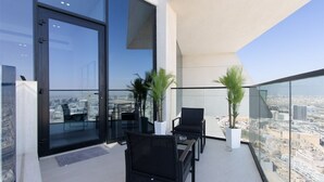 Ein moderner Balkon mit zwei Korbstühlen und einem Tisch, mit Blick auf eine Stadtlandschaft.
