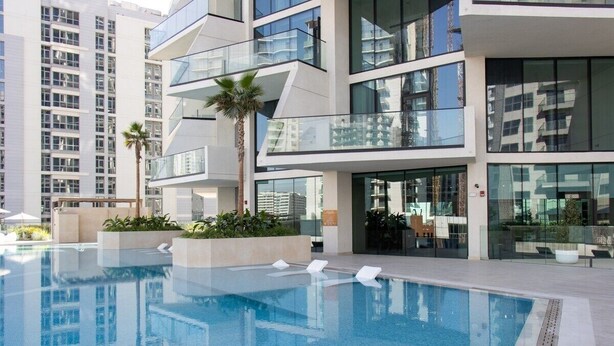 Ein modernes Hotel mit Dachpool, Glasbalkonen und Blick auf die umliegenden Gebäude.