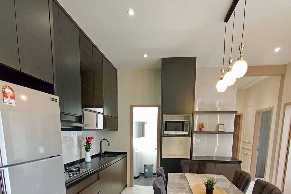 Een moderne keuken met een eethoek, roestvrijstalen apparatuur en een grote tafel.