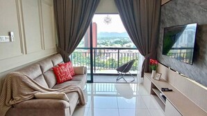 A modern living room with a sofa, TV, and balcony with a view. - The Horizon Ipoh Skyline By Grab A Stay (Ipoh)