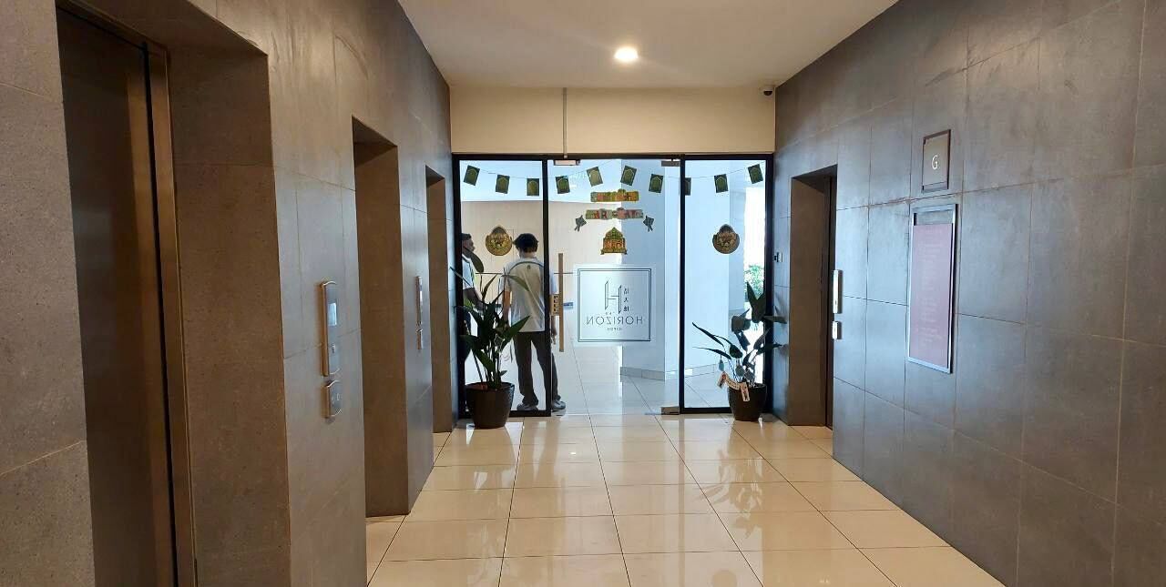 Un hall de hotel con suelo de baldosas, una recepción y puerta de cristal.