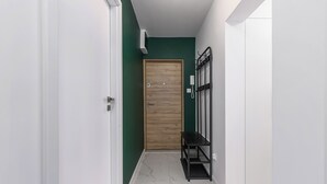 A hallway with a wooden door, a bench, and a wall-mounted phone. - Lumina 3-room apartment with balcony (Warsaw)