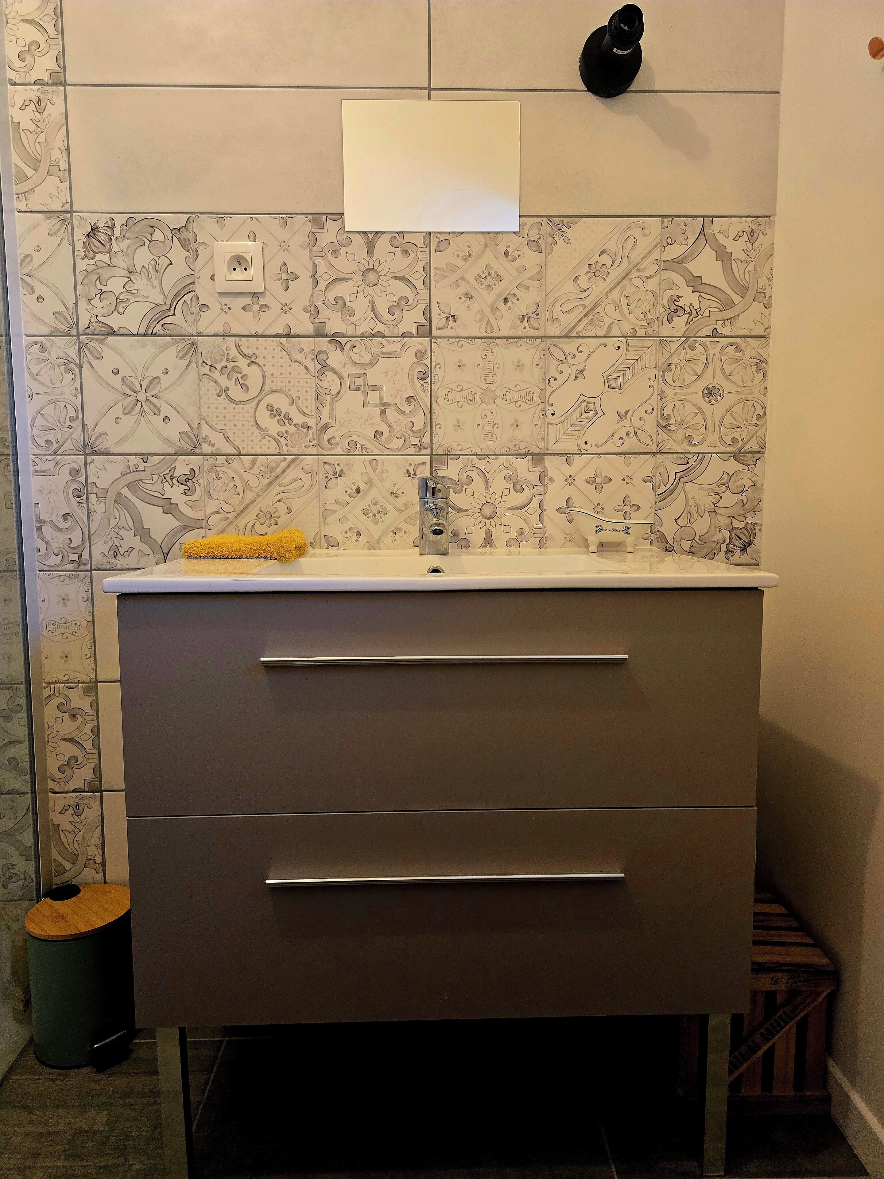 Een badkamer met een wastafel, een spiegel en betegelde vloeren.