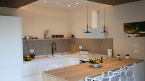 Een moderne keuken met een centraal eiland, witte stoelen en hanglampen.