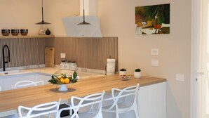 Een moderne keuken met een houten aanrecht, witte barstoelen en hanglampen.