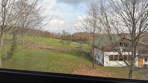 A view of a rural landscape with a house, a fenced area, and a grassy field.