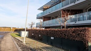 Moderni rakennus, jossa on tasakatto, suuret ikkunat ja metallikaide ylemmällä tasolla.