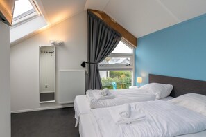 A hotel room with two beds, a skylight, a window with curtains, a radiator, and a view of greenery outside. - 6-Person Holiday Home in Renesse (Renesse)