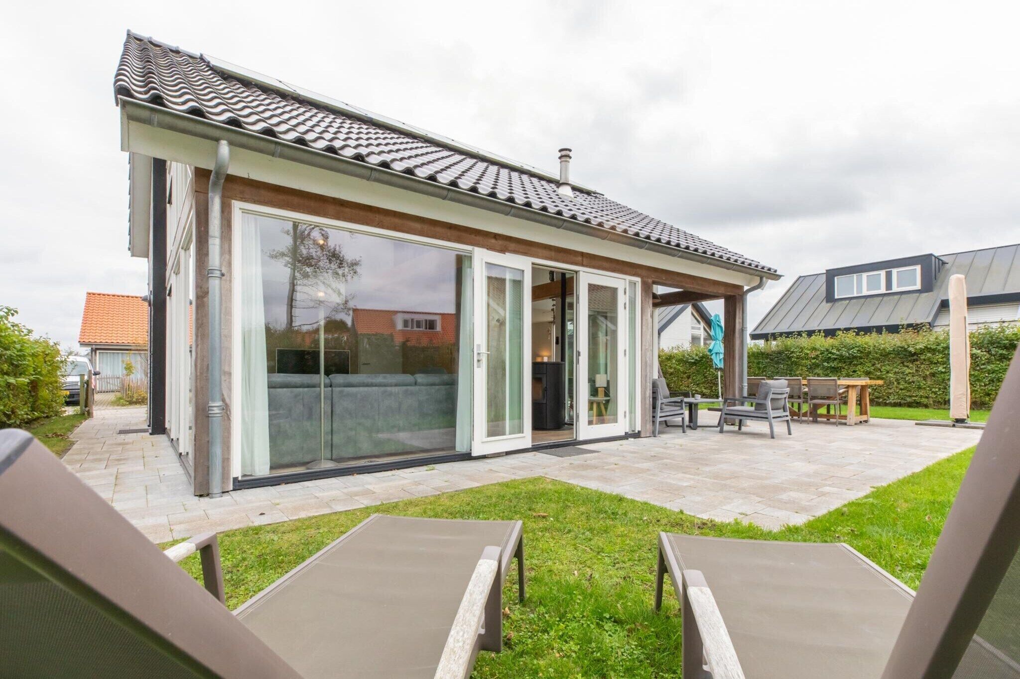 A modern house with a patio area, large sliding glass doors, and a covered outdoor seating area.