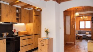 Una cucina moderna con mobili in legno, un piano di lavoro nero e un piccolo armadietto in legno con un vaso di fiori.