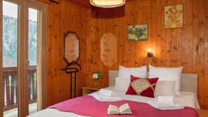 Camera da letto con pannelli in legno, un letto, cuscini, un comodino con un vaso e un attaccapanni a parete.