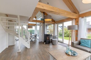 A spacious living area with a staircase, a fireplace, and a view of the outdoors. - Beachside Modern Holiday Home for 6 (Renesse)