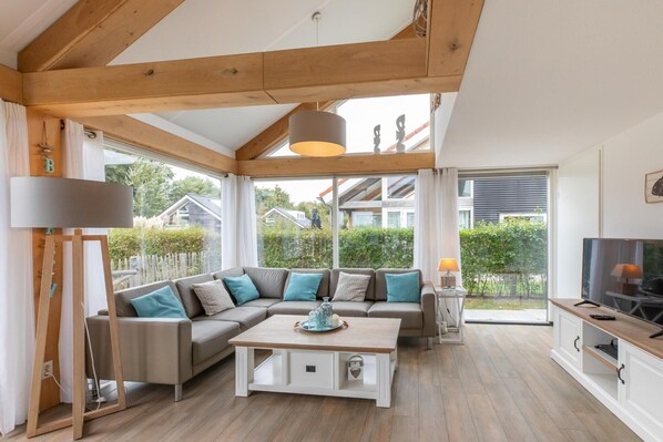 A modern living room with a sectional sofa, a coffee table, and a TV stand. - Beachside Modern Holiday Home for 6 (Renesse)