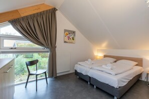 Ein Schlafzimmer mit einem Bett, einem Sessel, einem Schreibtisch und einem Fenster mit Vorhängen.