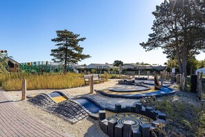 Ein Spielplatz mit einer runden Spieleinheit, Bänken und einem umzäunten Garten.