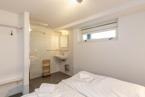 Ein Hotelzimmer mit Bett, Dusche, Waschbecken und Fenster.