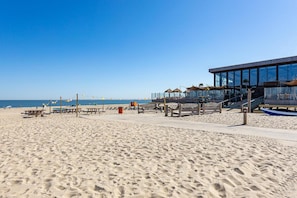 A beach with a modern building, picnic tables, and umbrellas. - Wonderful Beach Holiday Home for 6 (Renesse)