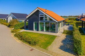 A modern two-story house with a sloped roof, large windows, and a well-maintained lawn. - Wonderful Beach Holiday Home for 6 (Renesse)