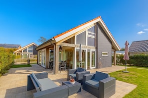 A modern house with a patio area featuring outdoor furniture and a dining table. - Wonderful Beach Holiday Home for 6 (Renesse)