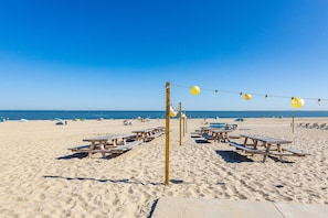 Ein Strand mit Picknicktischen und einem Volleyballnetz.