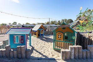 A sandy play area with colorful wooden playhouses and a climbing structure. - Wonderful Beach Holiday Home for 6 (Renesse)