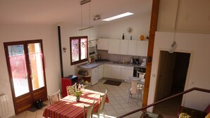 A kitchen with white cabinets, a dining area with a striped tablecloth, and a red sofa. - Le Gite de Jules at VIGNOT in LORRAINE near VERDUN, NANCY and METZ (Vignot)