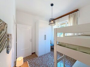 Ein Zimmer mit einem Etagenbett, einer Tür, einem gemusterten Boden und einer hängenden Leuchte.