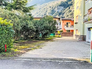 Eine Wohnstraße mit Häusern, einem Feldweg und einem Berg im Hintergrund.