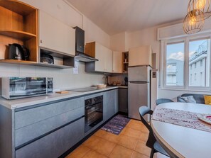 A modern kitchen with a microwave, oven, and refrigerator. There is a dining area with a table and chairs. - Lovely apartment for 8 guests with WIFI, TV and patio (Riva Del Garda)
