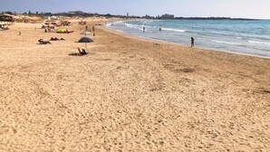 Una amplia playa de arena con sombrillas y gente.