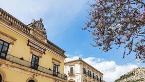 Un edificio histórico con una torre de reloj, ventanas de arco y un balcón.