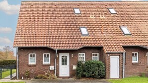 Et toetagers murhus med tegltag, ovenlysvinduer og en hoveddør.