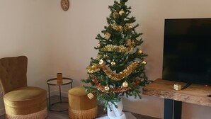 Ett vardagsrum med en julgran, en tv, en fåtölj och ett litet bord.