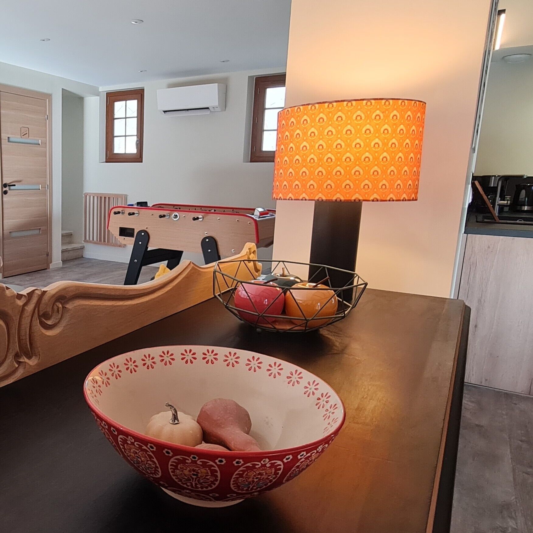 Un comedor con mesa de madera, un cuenco de fruta, una lámpara y un radiador.