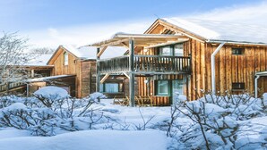 En træhytte med balkon og overdækket veranda, omgivet af sne.