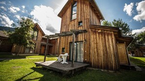 A wooden cabin with a deck and a small table, surrounded by a grassy yard. - Superior vacation home with gallery (St. Georgen am Kreischberg)