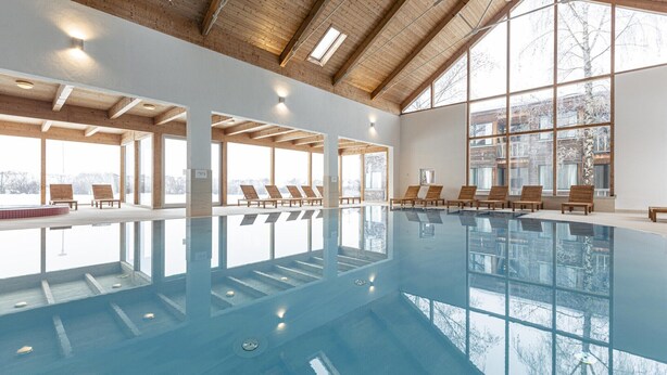 An indoor swimming pool with wooden deck chairs, large windows, and a high ceiling with skylights. - Superior vacation home with gallery (St. Georgen am Kreischberg)