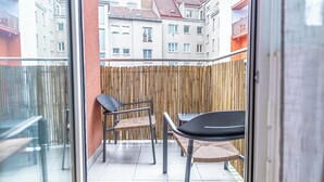 A balcony with a bamboo fence, two wicker chairs, and a table. - Nice 1BR 1LR Apartment City Center (Vienna)