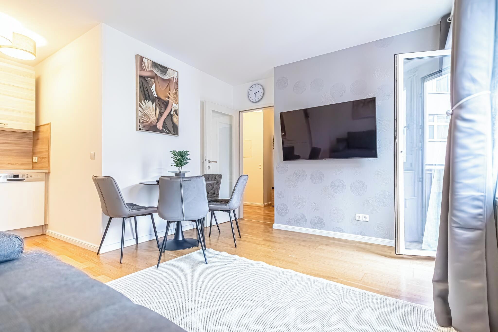 Un salon moderne comprenant un coin repas, un téléviseur à écran plat fixé au mur et un plancher en bois.