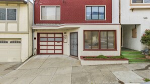 A two-story house with a garage, a front door, and a small front yard with a planter. - 3 Bedroom/ 2Bathroom House, Walkable to BART, Free parking, Game Room, and Views (Daly City)