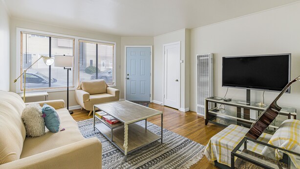 A living room with a sofa, coffee table, TV, and a guitar. - 3 Bedroom/ 2Bathroom House, Walkable to BART, Free parking, Game Room, and Views (Daly City)