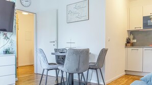 Una cocina moderna con armarios blancos, un comedor con sillas tapizadas en gris, y una cita motivacional en la pared.