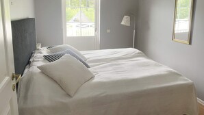 A bedroom with a bed, a door, a window, and a lamp. - 5 Star Holiday Home in Vaxholm (Vaxholm)